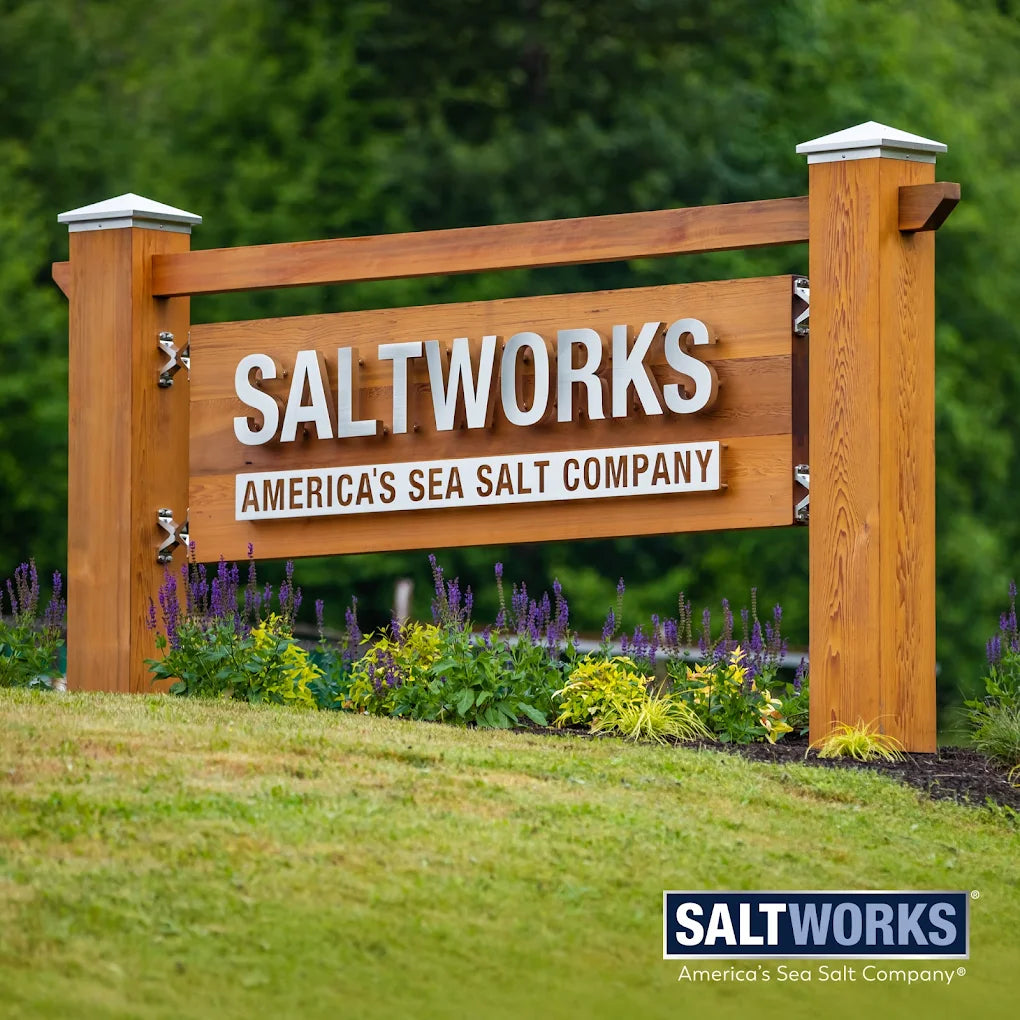 Wooden sign for Saltworks America's Sea Salt Company with a blurred green background