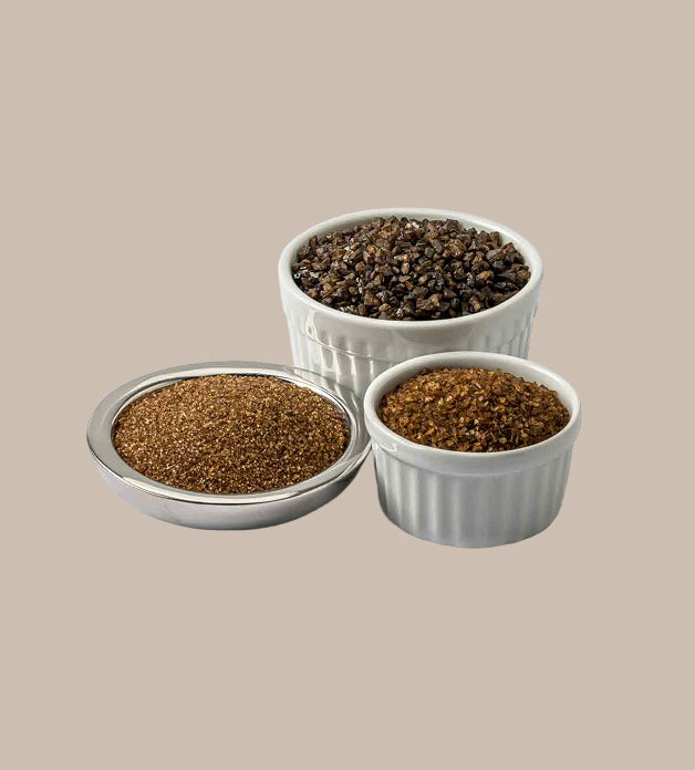 Three small white ramekins filled with different types of smoked salt