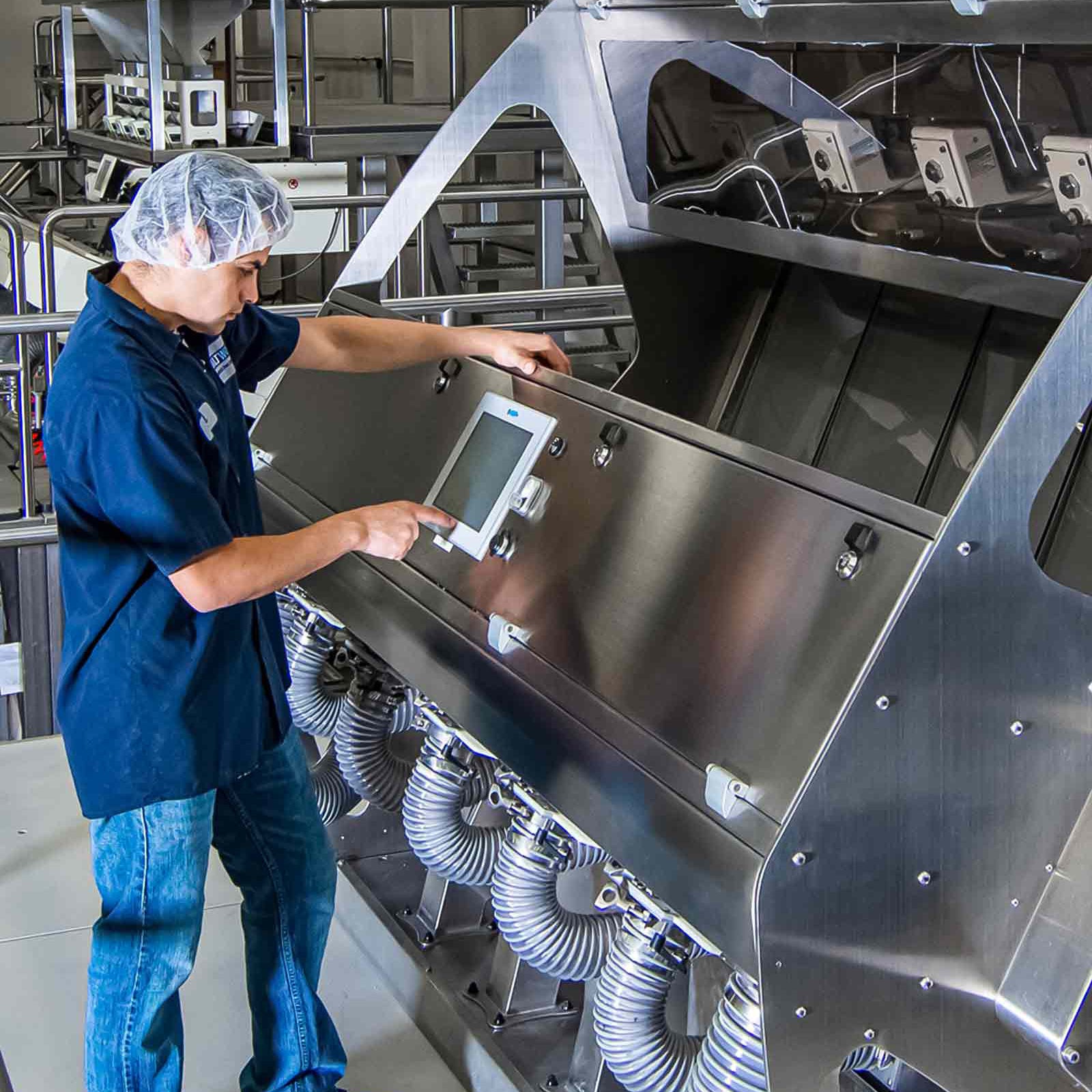 Person operating a large industrial machine with a digital display in a factory setting