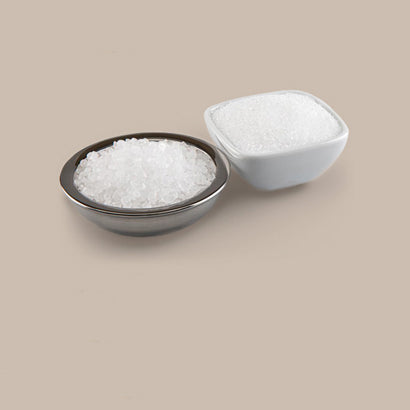 Two containers of white salt on a beige background