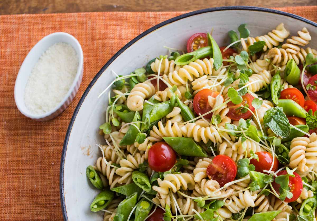 Pasta salad with mint and tomatoes next to a bowl of lemon salt