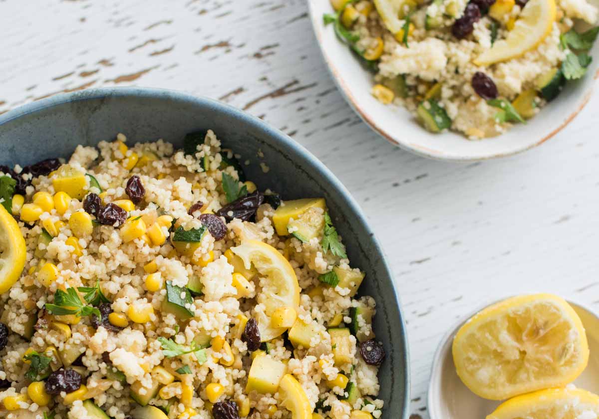 Quinoa salad with lemon, corn, and raisins in blue bowl