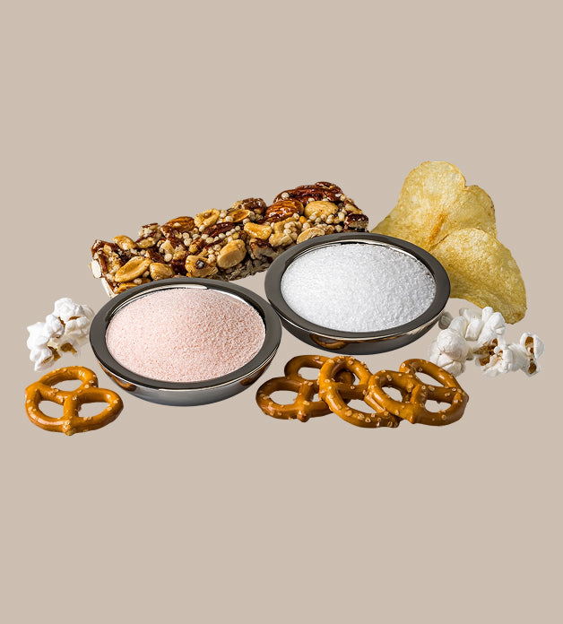 Assorted snack items including pretzels, popcorn, and nuts on a beige background