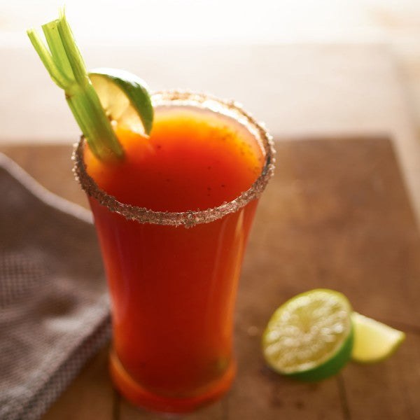 Glass of Bloody Mary with celery and lime on a wooden surface