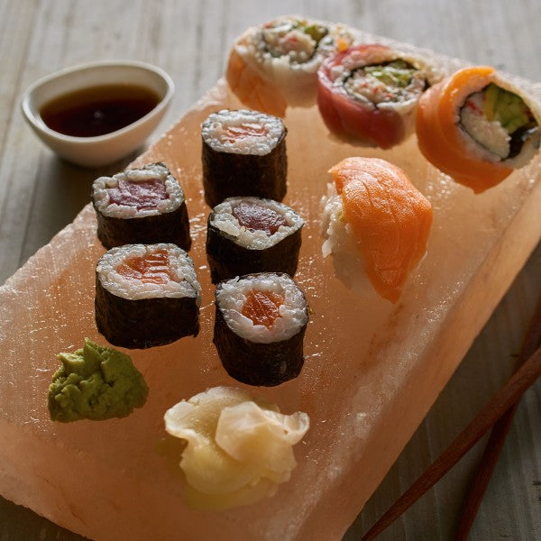 Assorted sushi on a salt block with soy sauce and wasabi.