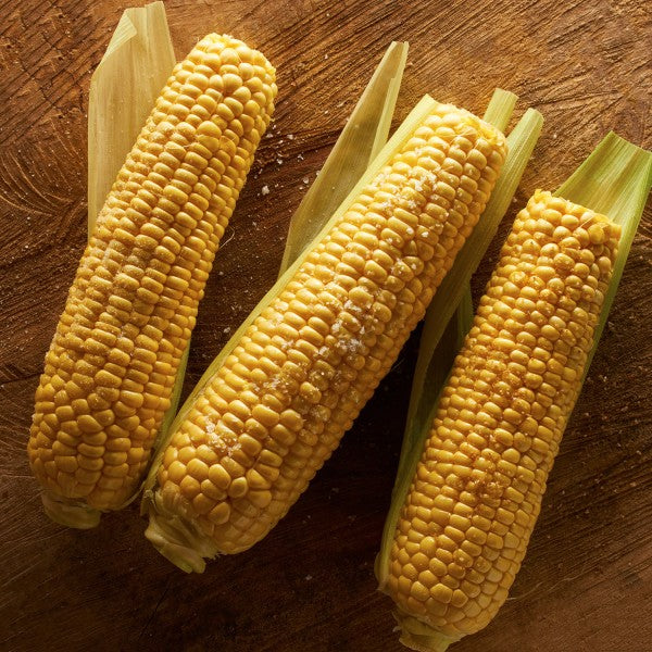 Three ears of corn on a wooden surface