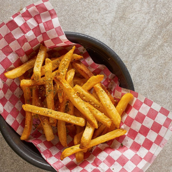 Basket of seasoned french fries on a checkered paper with a neutral background