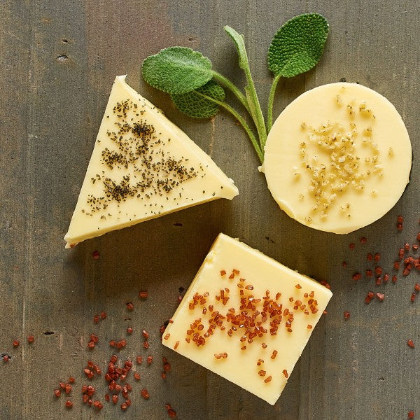 Three types of cheese with herbs and spices on a wooden surface
