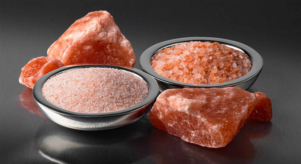 Himalayan salt in stainless steel bowls next to Himalayan salt chunks