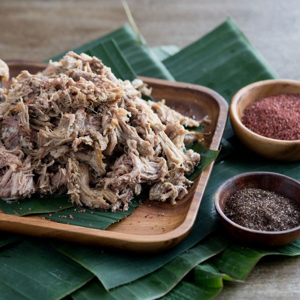 Shredded meat on a wooden plate with spices on a green leafy background
