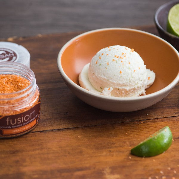 Ice cream in a bowl with a jar of fusion salt on a wooden surface.