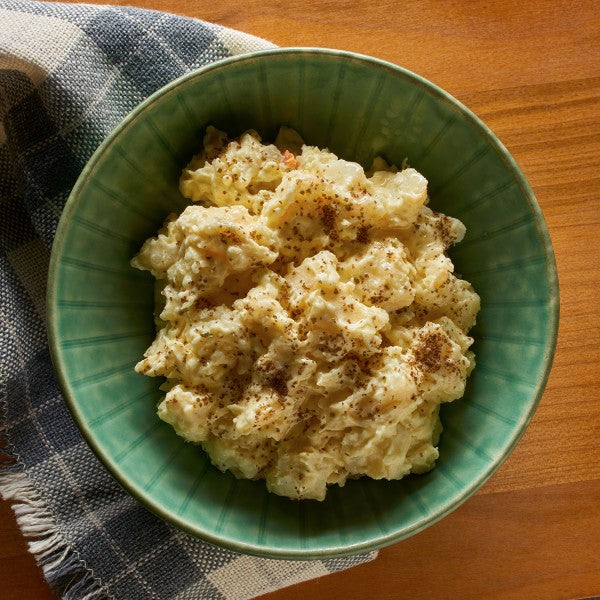Green bowl with mashed potatoes on a wooden surface