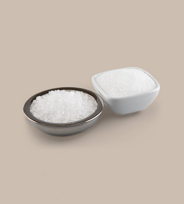 Bowl and container of white granulated sugar on a beige background