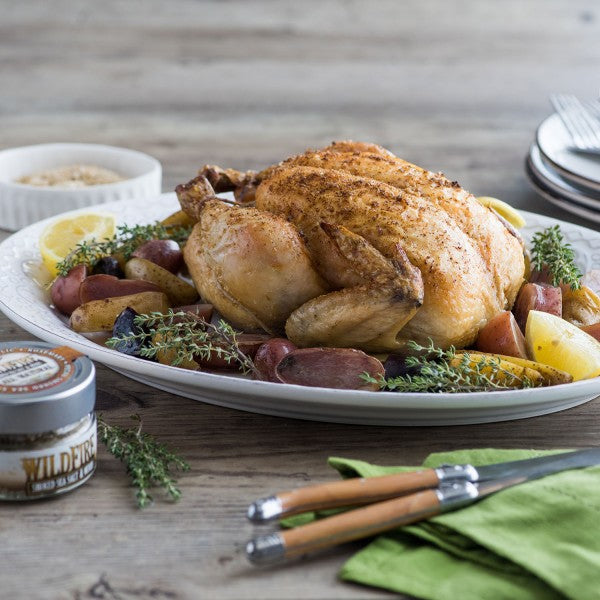 Roasted chicken with vegetables on a plate with a wooden background