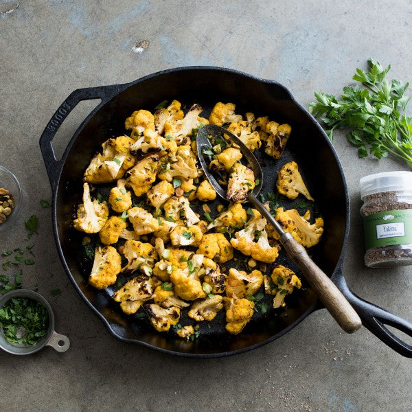 Roasted cauliflower in a black cast iron skillet on a concrete surface