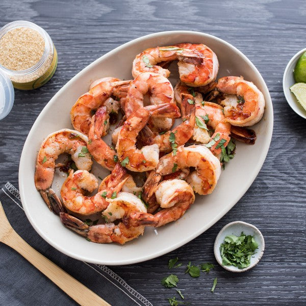Platter of grilled shrimp with seasonings on a dark surface