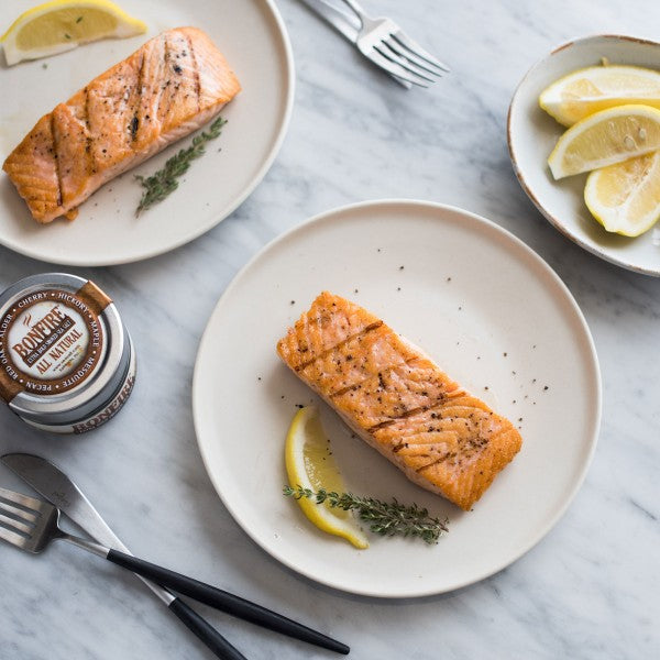 Seared salmon on a white plate with lemon and thyme 