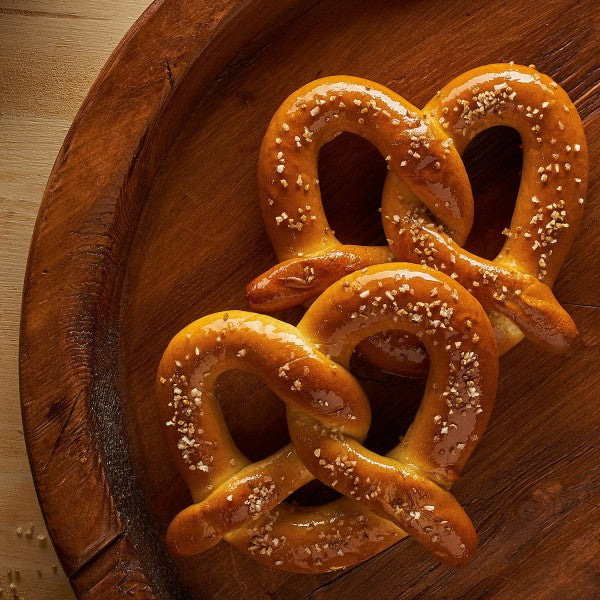 Three pretzels with salt on a wooden plate