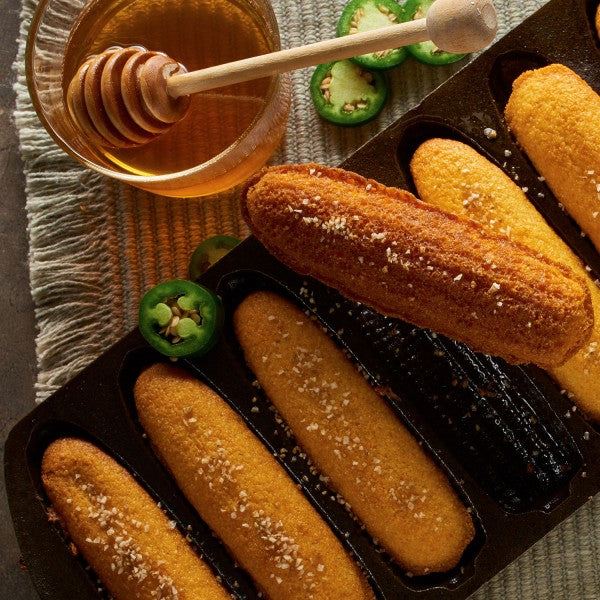 Corn bread in a pan with honey and jalapeños on the side