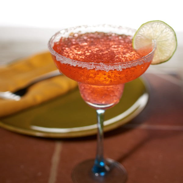 Pink cocktail in a martini glass with a lime wedge on a blurred background