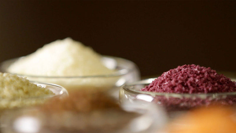 Glass bowls with different flavored salts on a dark background