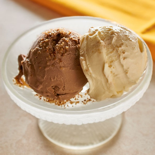 Two scoops of ice cream, one chocolate and one vanilla, on a white pedestal dish.